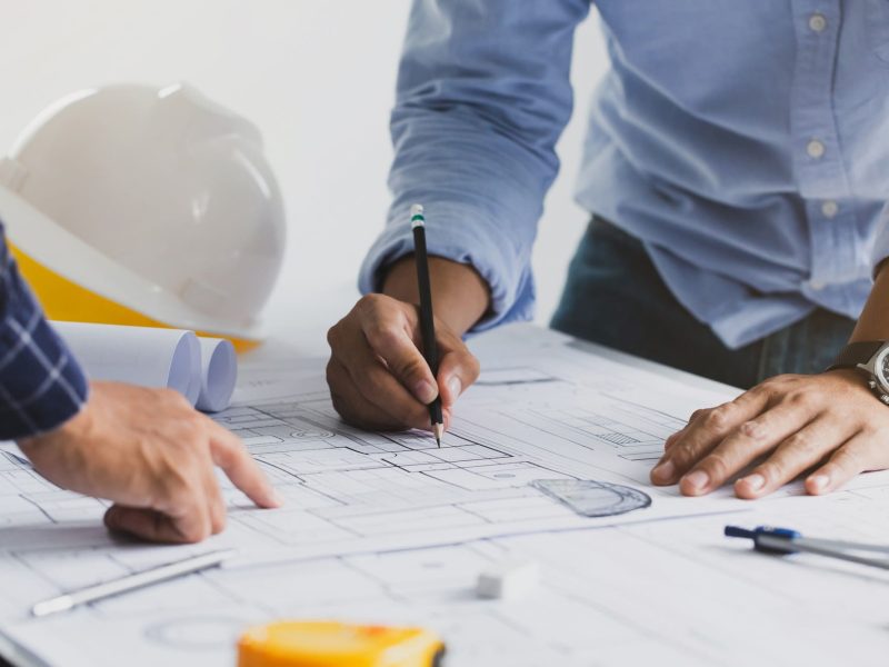 Deux professionnels en train d’analyser un plan de bâtiment pour planifier des interventions à long terme