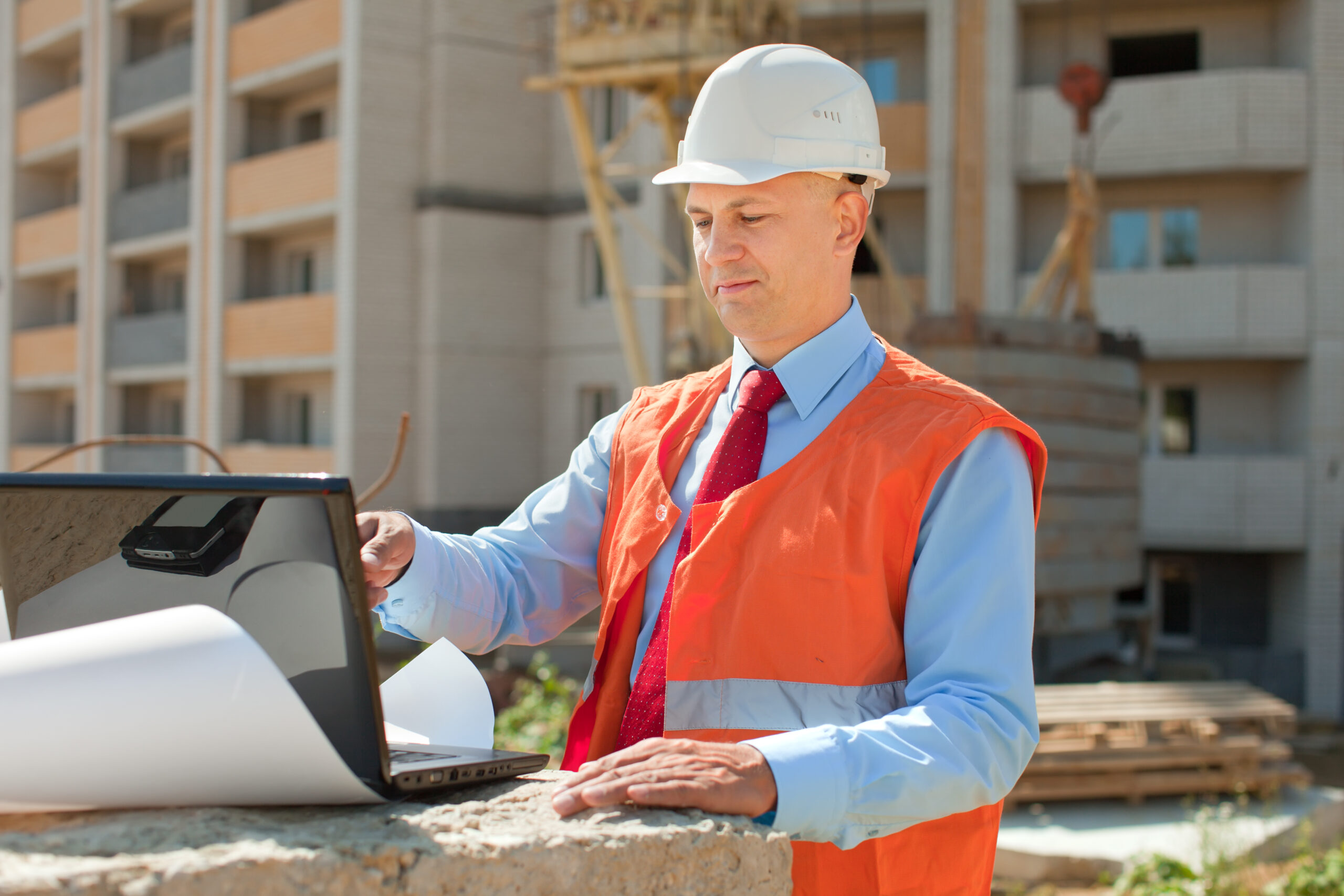 Portrait of white-collar worker wearing protective helmet works on the building site